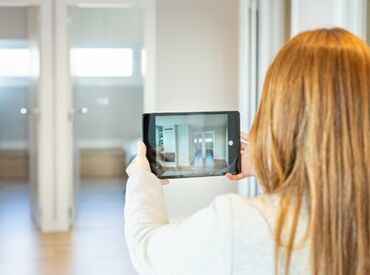 Junge Frau macht Fotos mit einem IPad in einer sanierten Wohnung