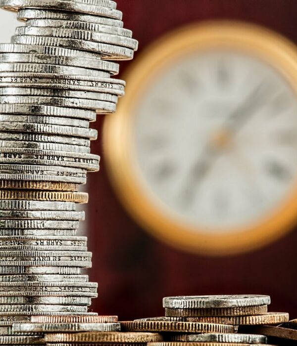 Zeit und Geld Münzen vor einer Wanduhr