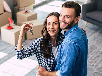 Glückliches Pärchen mit Umzugskartons und dem Wohnungsschlüssel