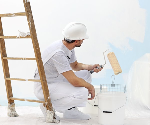 Maler streicht Wand mit Malerrolle in weißer Farbe. Maler streicht Wand mit Malerrolle in weißer Farbe.