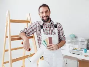 Malermeister hält Farbauswahl und Malerrolle in der Hand