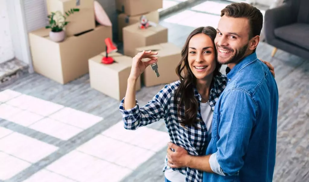 Fröhliches Pärchen hält die Schlüssel zur neuen Wohnung in der Hand.