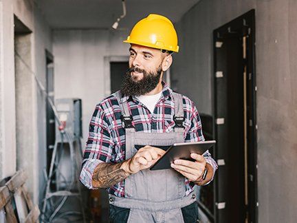 Handwerker begutachtet Baustelle mit Tablet