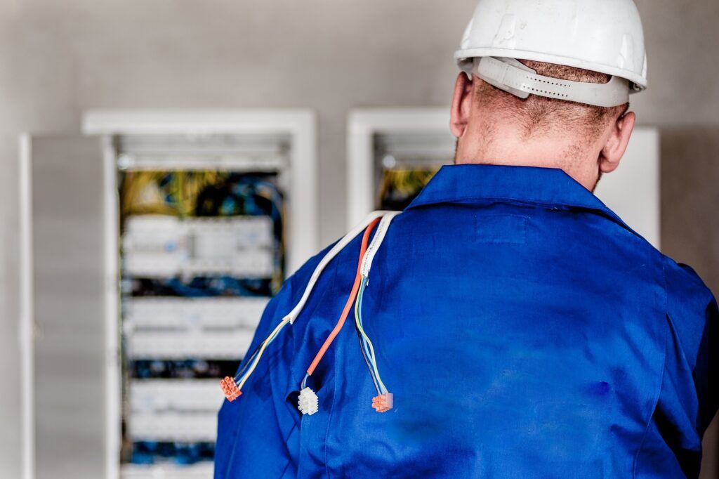 Elektriker steht vor einem Sicherungskasten