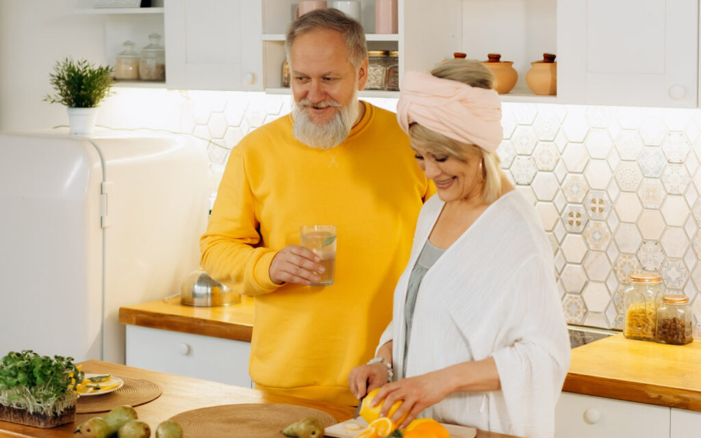 älteres Paar bereitet Essen in schöner, hellen Küche in Weiß und Holz vor