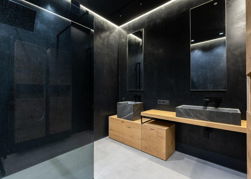 fugenloses Badezimmer in dunklen Farbtönen und Holzmöbeln